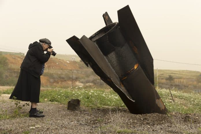 אמיר לוי, אישה מצלמת חלק של טיל שנורה מאיראן שנפל סמוך לרפת בשדמות מחולה שבבקעת הירדן, 3.4.2026